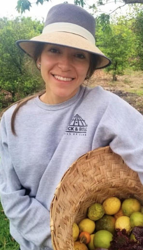 Paz pictured wearing a hat and holding a basket of fruit.